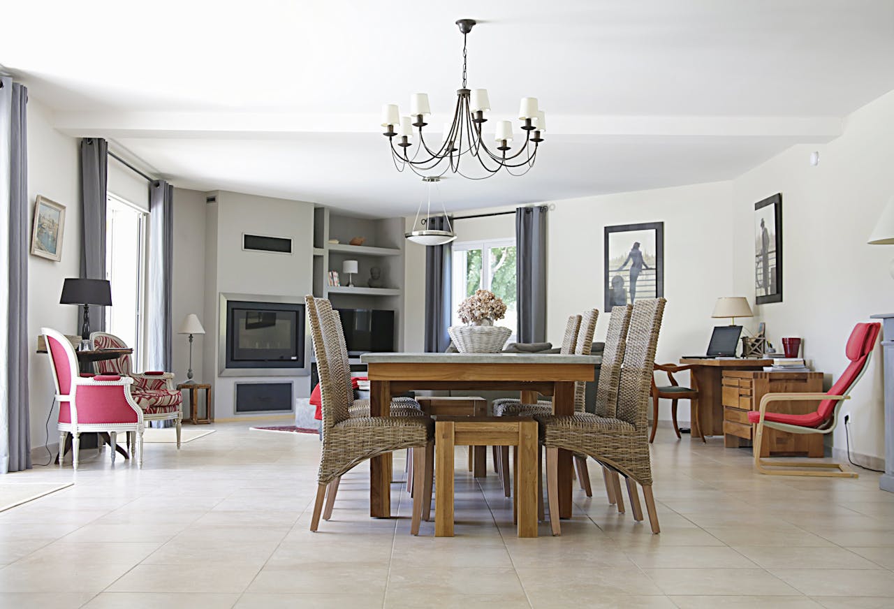 services-img Spacious dining room with a chic chandelier, wicker chairs, wooden table, and cozy fireplace.