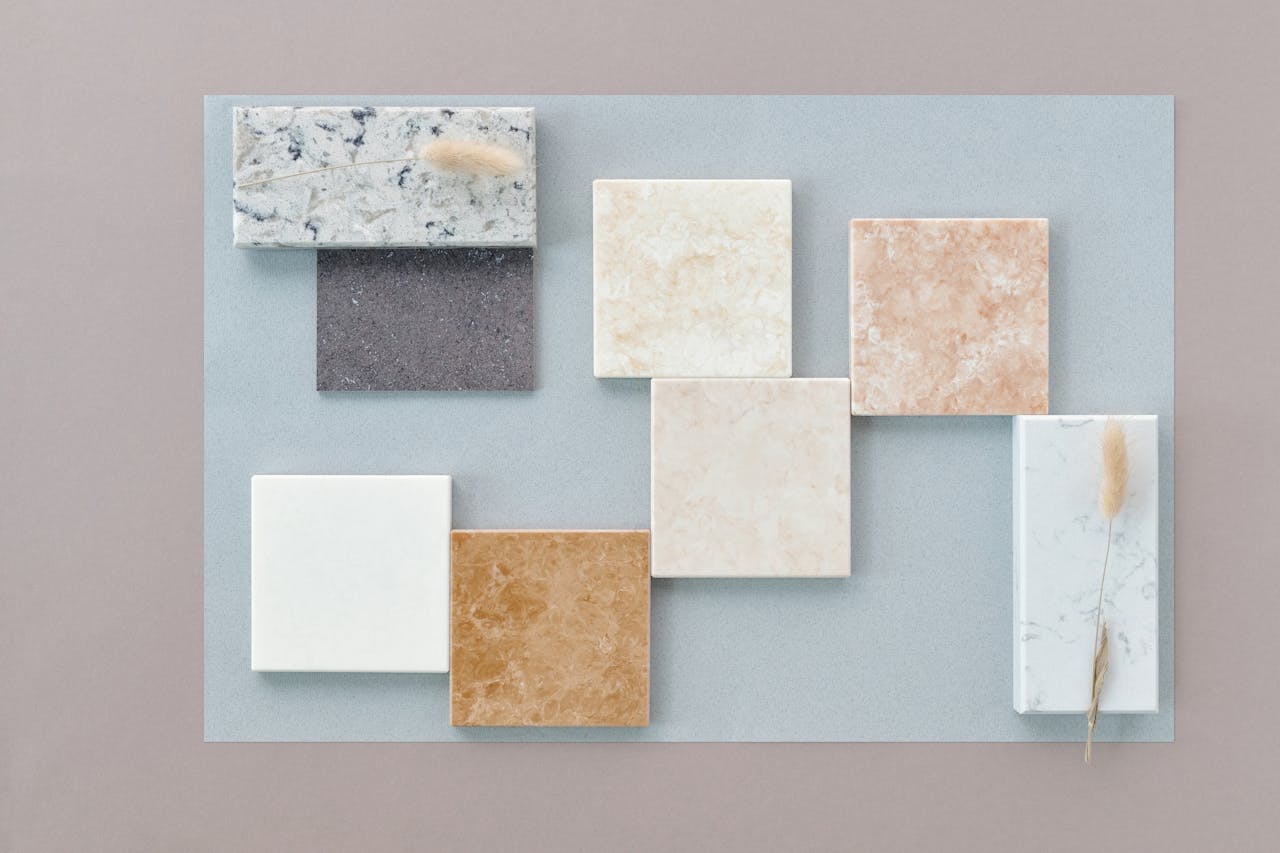 A flat lay of various marble tiles on a neutral background, showcasing diverse textures and colors.