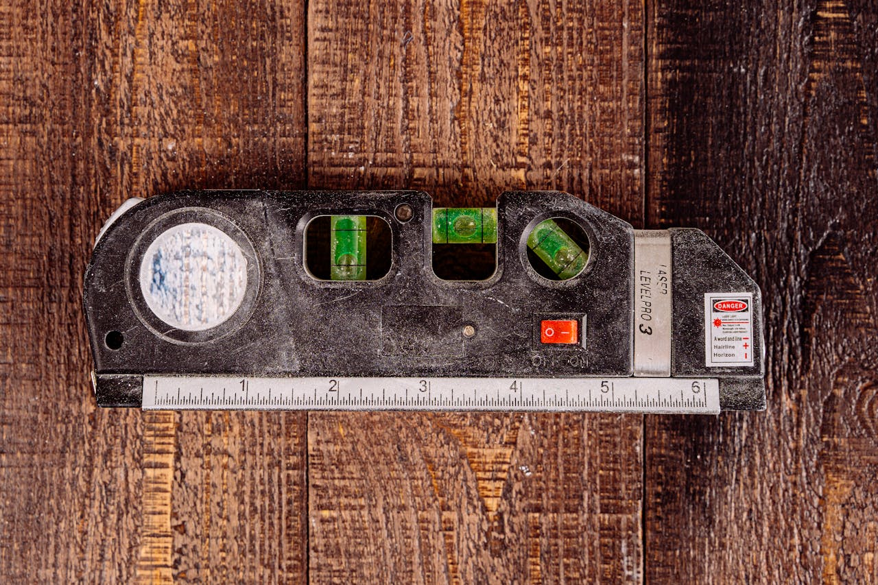 services-04 Close-up of a multipurpose laser level tool on a wooden table surface.