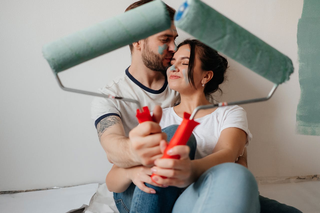 A couple enjoying a moment while painting their home, symbolizing love and teamwork.